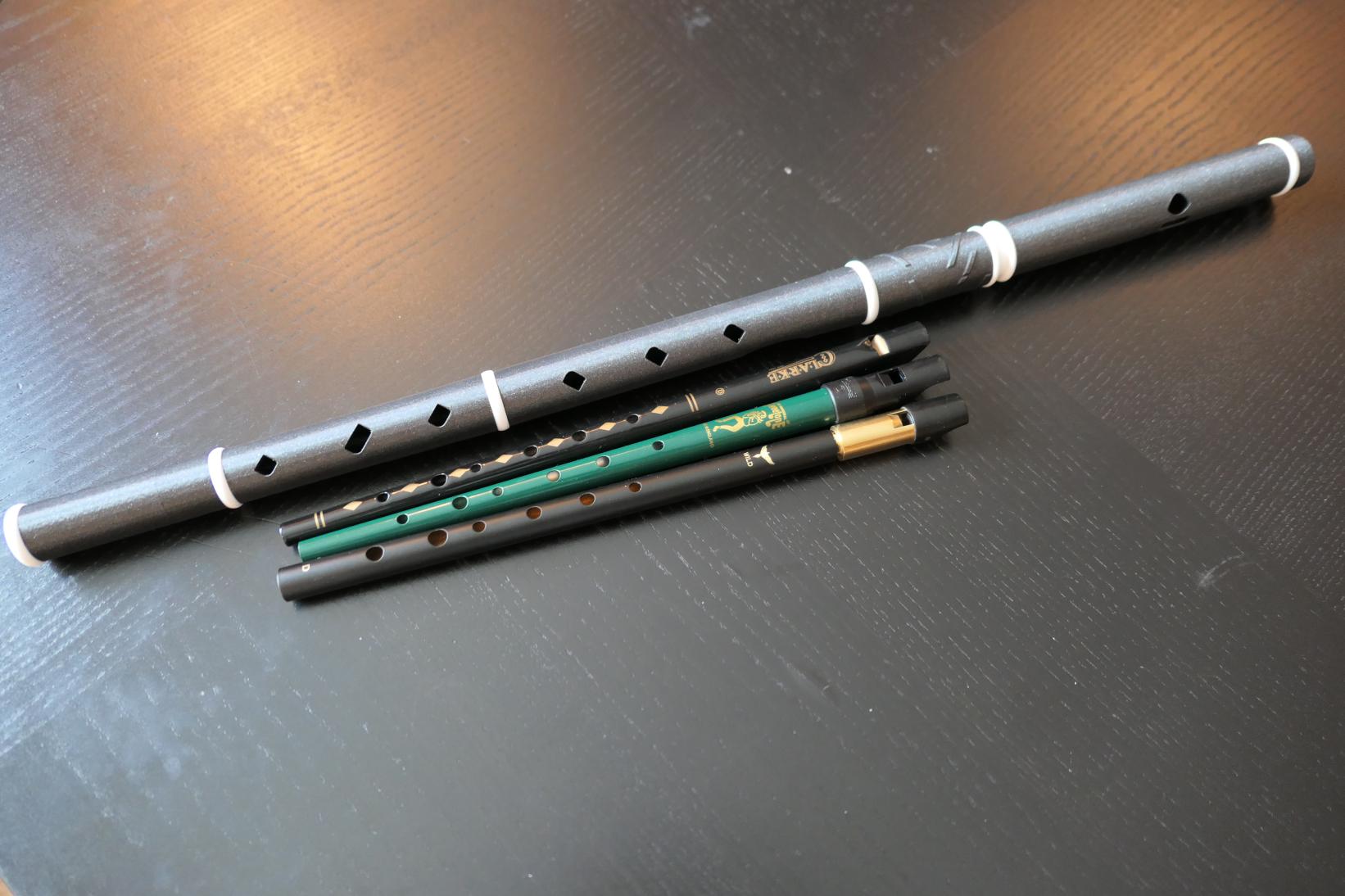 A black plastic Irish flute, and three tin whistles