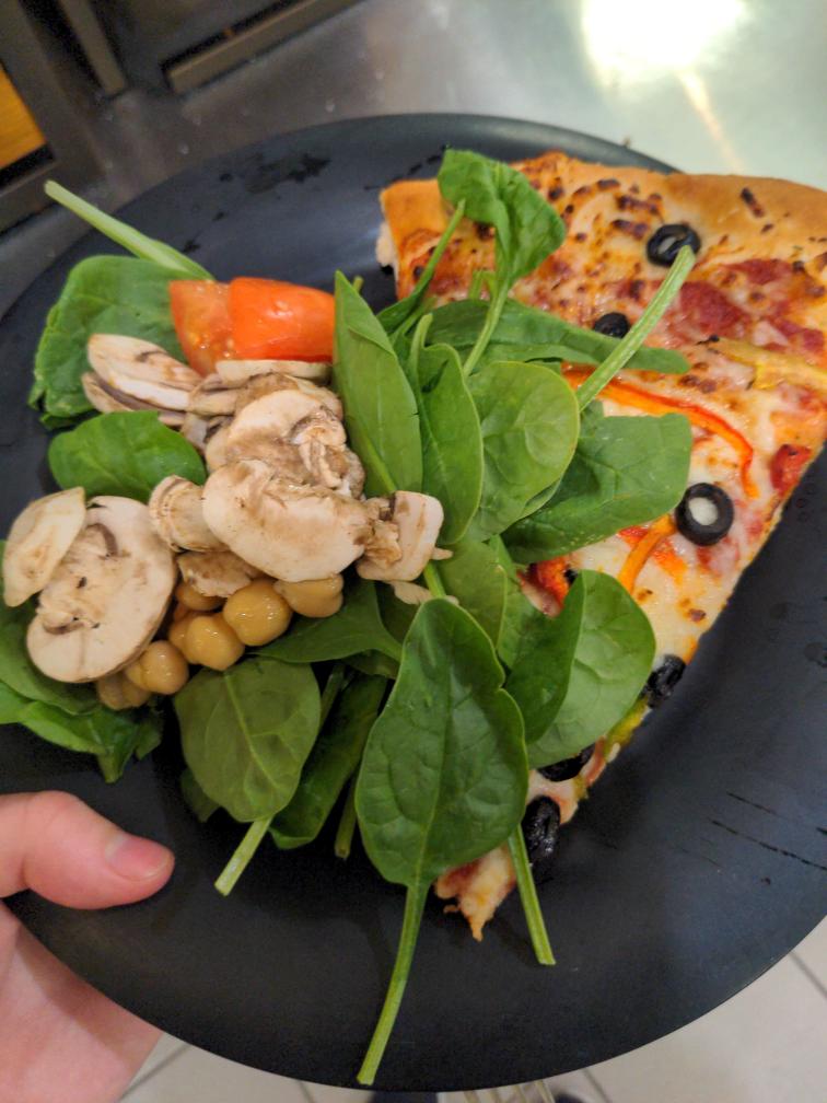 Combo of raw veggies next to slice of pizza